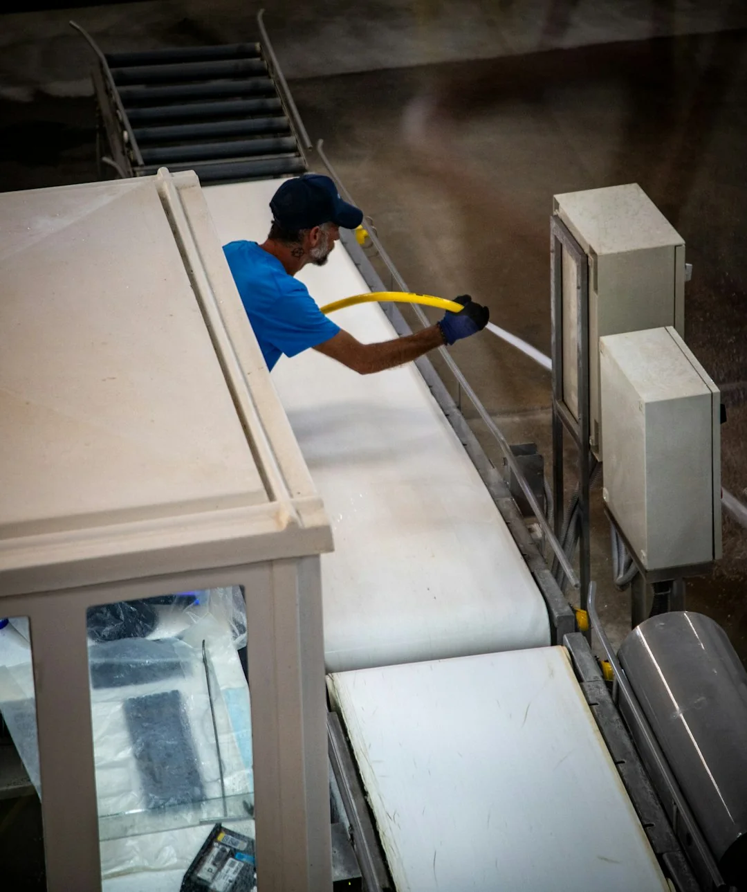 Person using spray bottle and cloth for cleaning a kitchen shelf, ensuring hygiene and cleanliness.